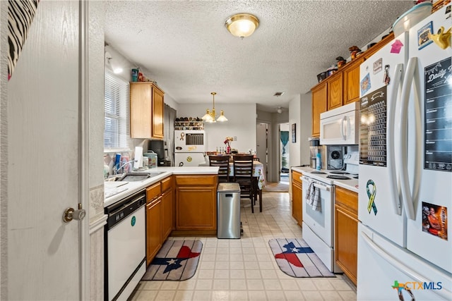 kitchen with sink, a notable chandelier, a textured ceiling, decorative light fixtures, and white appliances