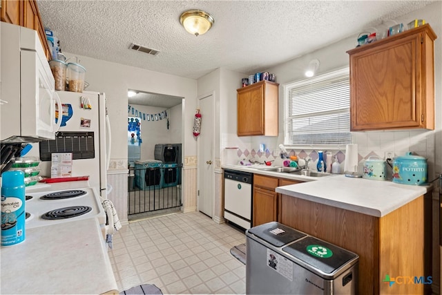 kitchen featuring a textured ceiling, decorative backsplash, white appliances, and sink