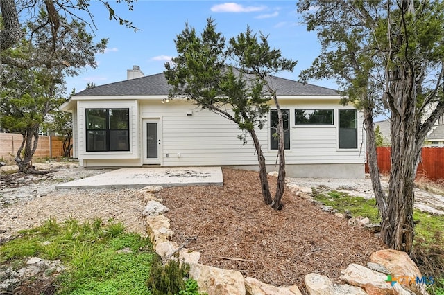 back of house featuring a shingled roof, fence, a chimney, and a patio