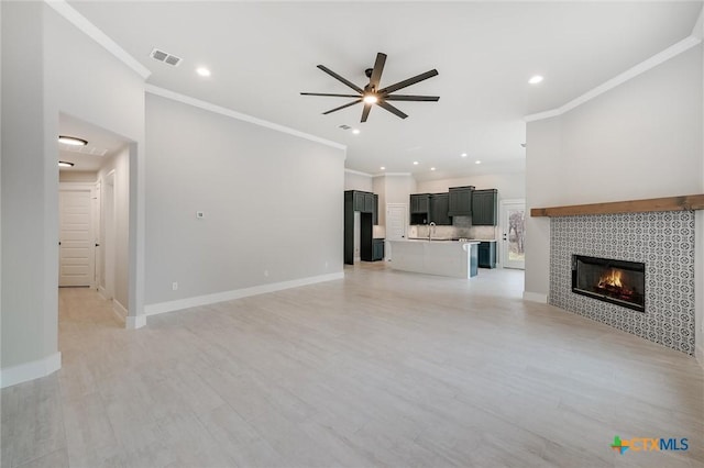 unfurnished living room featuring baseboards, visible vents, a ceiling fan, and a tile fireplace