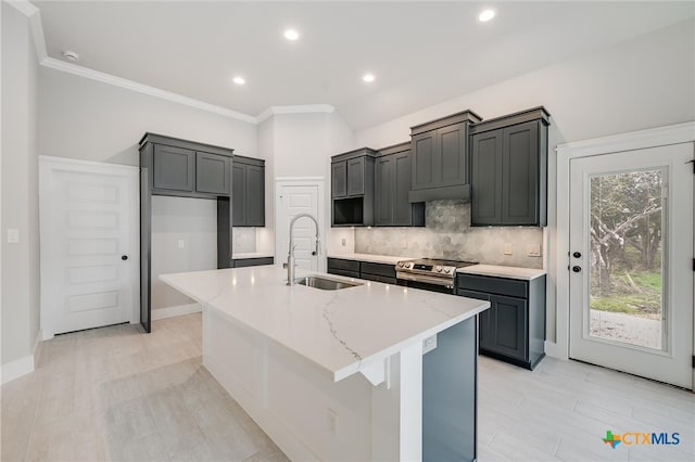 kitchen featuring electric stove, decorative backsplash, a sink, an island with sink, and light stone countertops