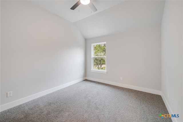 carpeted spare room featuring vaulted ceiling, baseboards, and ceiling fan