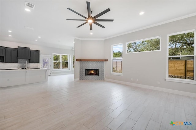 unfurnished living room featuring ceiling fan, visible vents, baseboards, light wood finished floors, and a tiled fireplace