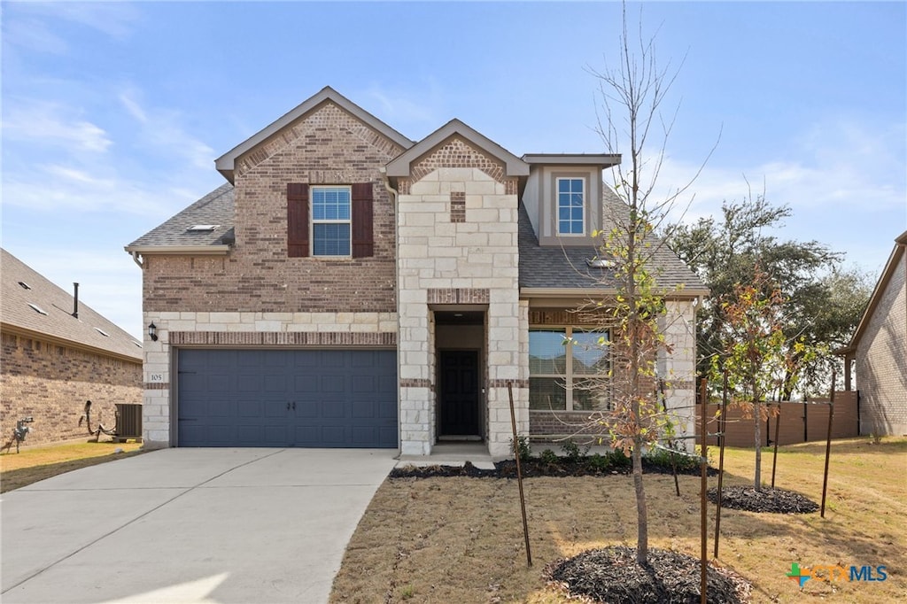 french country inspired facade with a shingled roof, driveway, stone siding, a garage, and central AC unit