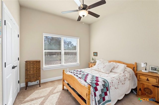 bedroom with a closet, light colored carpet, ceiling fan, and baseboards