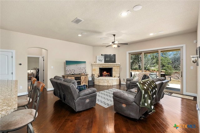 living area featuring visible vents, a fireplace, arched walkways, and hardwood / wood-style floors