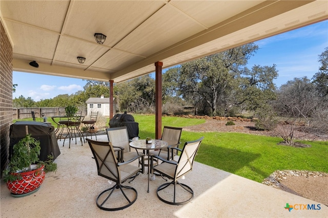 view of patio with grilling area, fence, outdoor dining area, and an outbuilding