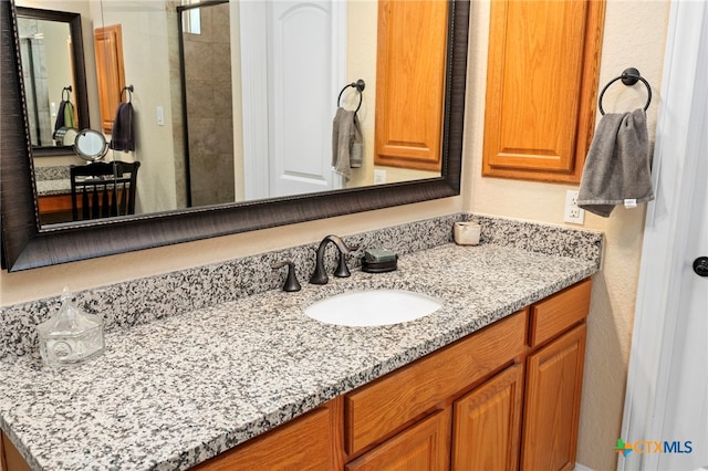 bathroom featuring tiled shower and vanity