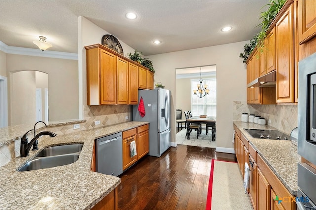 kitchen with under cabinet range hood, stainless steel appliances, dark wood-style flooring, a sink, and light stone countertops