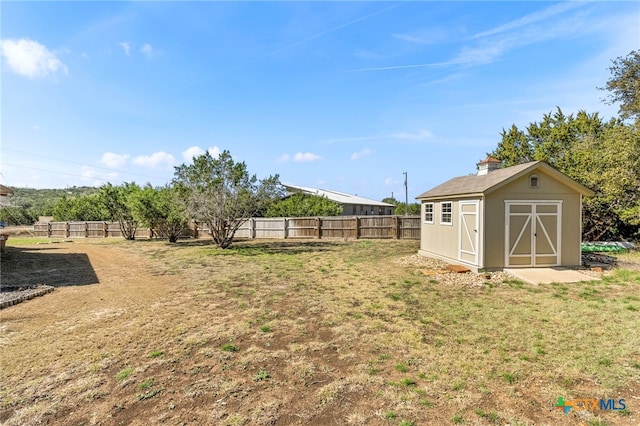 view of yard featuring a shed, a fenced backyard, and an outdoor structure