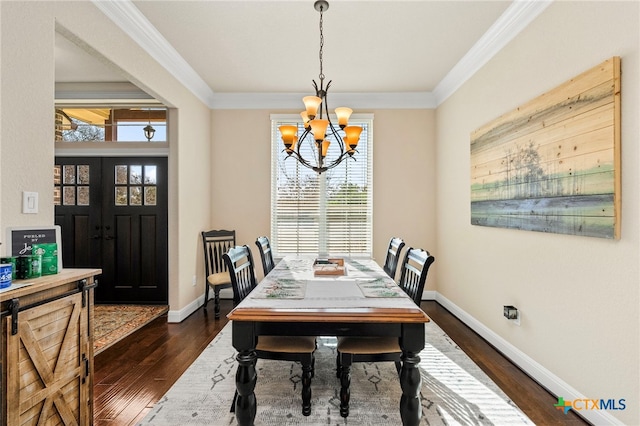 dining space with a healthy amount of sunlight, dark wood-style floors, crown molding, and a notable chandelier