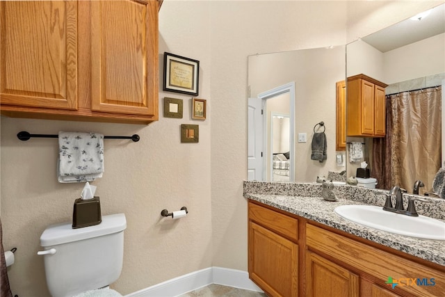 full bathroom with baseboards, vanity, and toilet