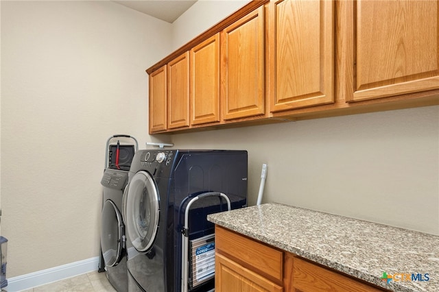 washroom with washing machine and dryer, cabinet space, and baseboards