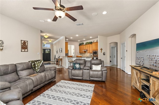 living room featuring dark wood-style floors, arched walkways, and recessed lighting