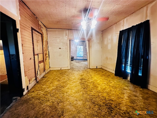 empty room featuring wood walls, carpet, and ceiling fan