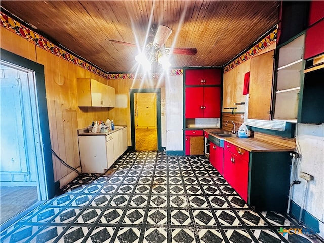 kitchen with butcher block countertops, wooden walls, sink, wood ceiling, and ceiling fan