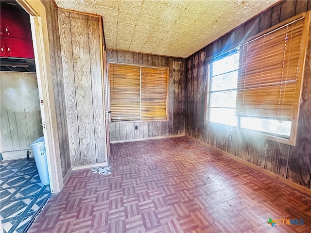 spare room featuring parquet flooring and wooden walls