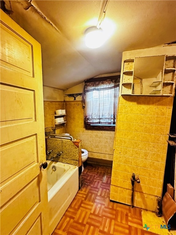 bathroom featuring tile walls, parquet flooring, toilet, and vaulted ceiling