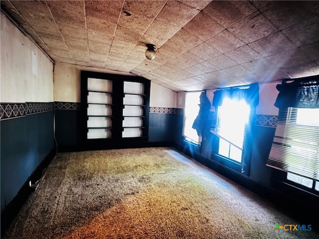 carpeted empty room featuring lofted ceiling