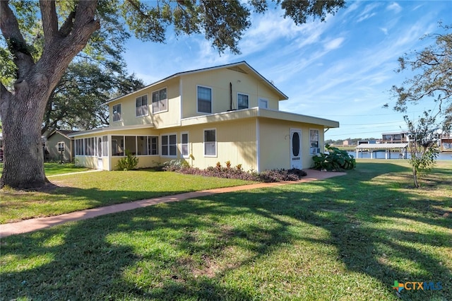 rear view of house with a lawn and a sunroom