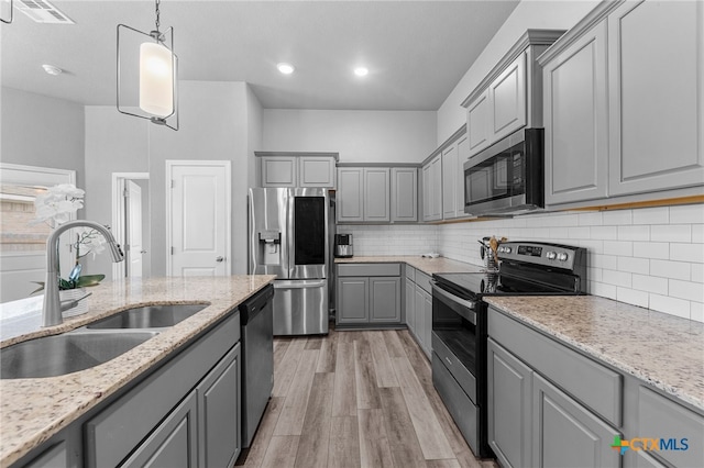 kitchen featuring gray cabinets, appliances with stainless steel finishes, light stone counters, and light hardwood / wood-style flooring