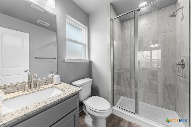 bathroom featuring toilet, vanity, wood-type flooring, and a shower with door