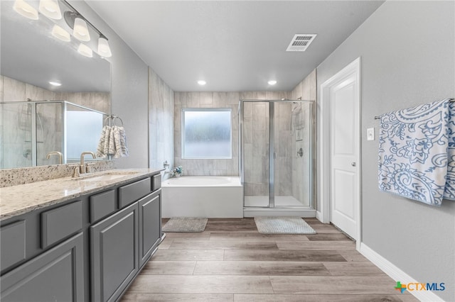 bathroom with plus walk in shower, vanity, and hardwood / wood-style flooring