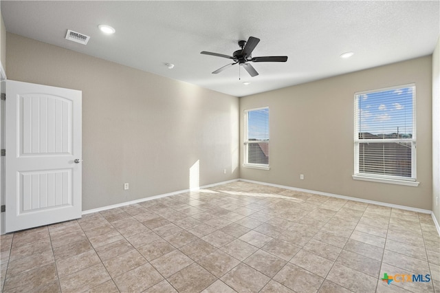 spare room with ceiling fan, light tile patterned floors, and a textured ceiling