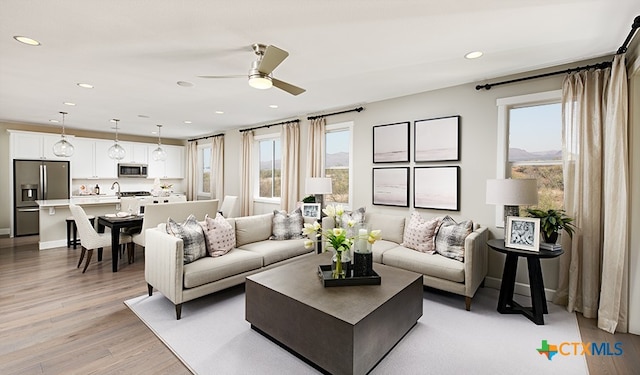 living room featuring ceiling fan and light wood-type flooring