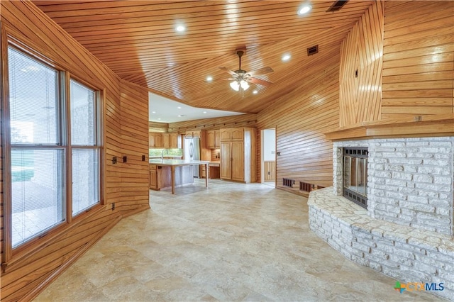 614 County Road 207, Burnet, TX 78611 - unfurnished living room featuring wooden walls, plenty of natural light, a fireplace, ceiling fan, and wood ceiling