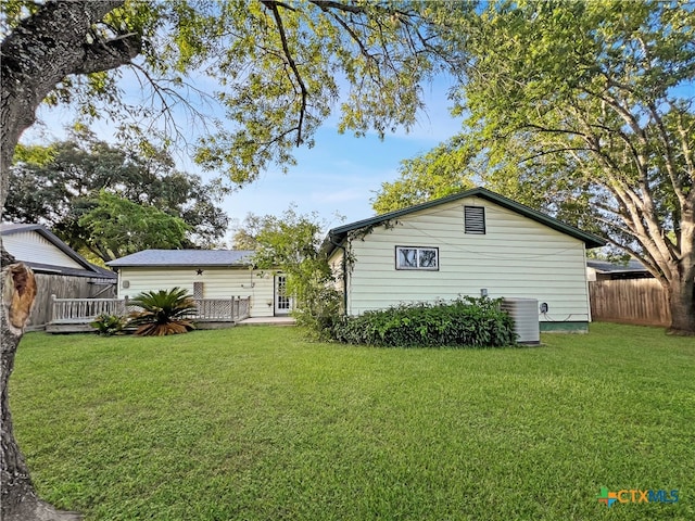 rear view of property featuring central air condition unit and a yard