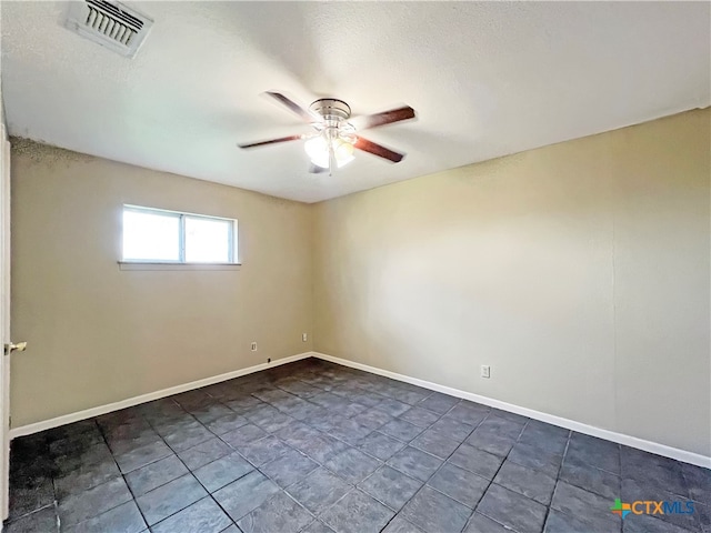 spare room featuring ceiling fan and dark tile patterned floors