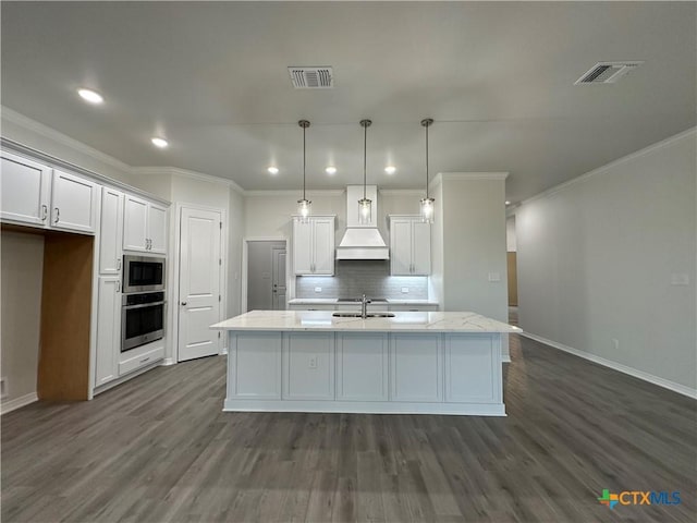 kitchen with a center island with sink, white cabinets, stainless steel appliances, and decorative light fixtures