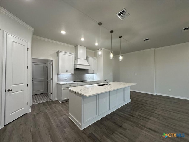 kitchen featuring white cabinetry, a center island with sink, decorative light fixtures, black electric cooktop, and custom exhaust hood