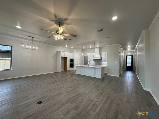 kitchen with white cabinetry, an island with sink, ceiling fan, dark hardwood / wood-style flooring, and hanging light fixtures