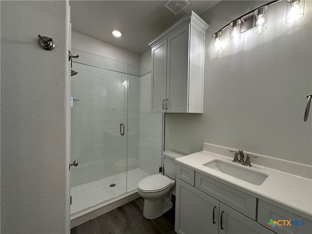 bathroom featuring toilet, hardwood / wood-style flooring, vanity, and a shower with door