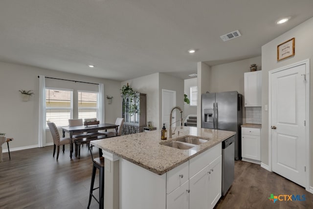 kitchen with white cabinetry, sink, stainless steel appliances, dark hardwood / wood-style flooring, and an island with sink