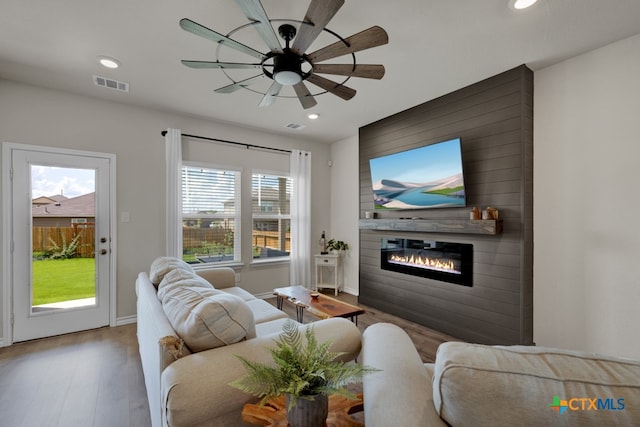 living room featuring a wealth of natural light, a large fireplace, ceiling fan, and hardwood / wood-style floors