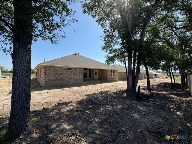 rear view of property featuring brick siding and fence
