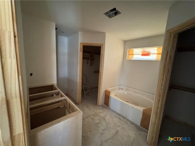 bathroom with a spacious closet and a garden tub