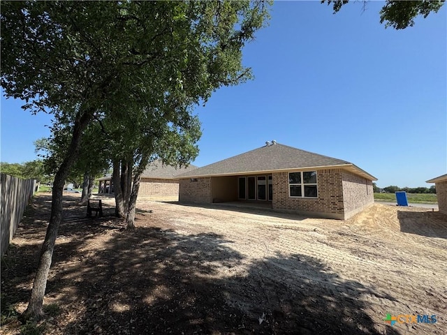back of property featuring brick siding and fence
