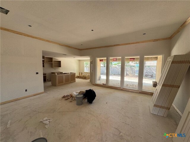 unfurnished living room featuring crown molding, baseboards, and a textured ceiling
