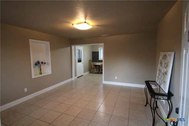 spare room featuring light tile patterned flooring and a textured ceiling