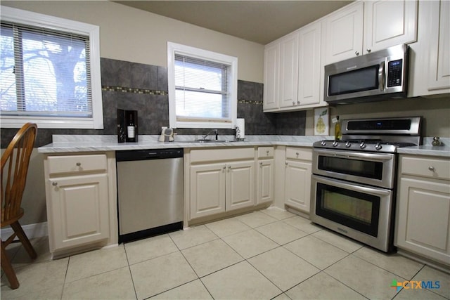 kitchen with a wealth of natural light, white cabinetry, stainless steel appliances, and light tile patterned floors