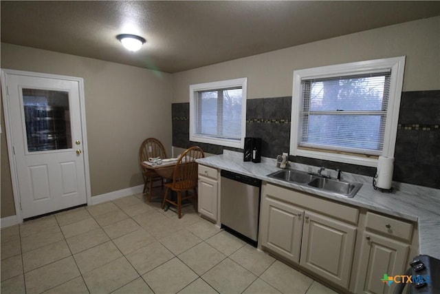 kitchen featuring light tile patterned floors, stainless steel dishwasher, plenty of natural light, and sink