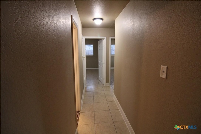 hall with light tile patterned flooring and a textured ceiling