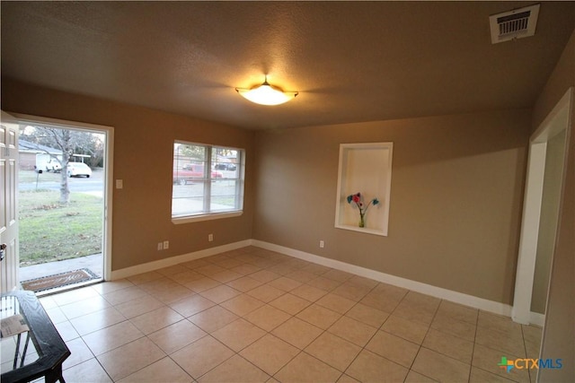 empty room with light tile patterned floors and a textured ceiling