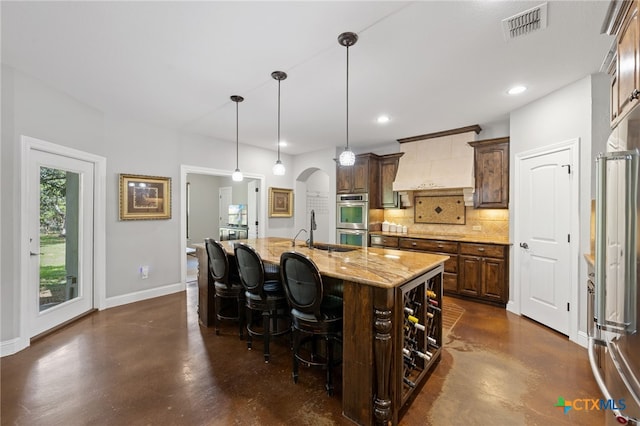 1448 Decanter Dr, New Braunfels, TX 78132 - kitchen with premium range hood, finished concrete floors, decorative backsplash, appliances with stainless steel finishes, and a kitchen island with sink