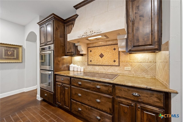 1448 Decanter Dr, New Braunfels, TX 78132 - kitchen featuring double oven, custom range hood, black electric stovetop, arched walkways, and dark brown cabinets