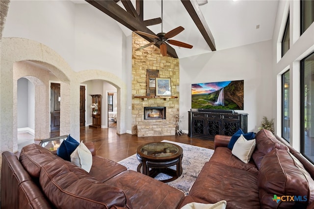 1448 Decanter Dr, New Braunfels, TX 78132 - living room featuring high vaulted ceiling, beam ceiling, ceiling fan, a stone fireplace, and arched walkways